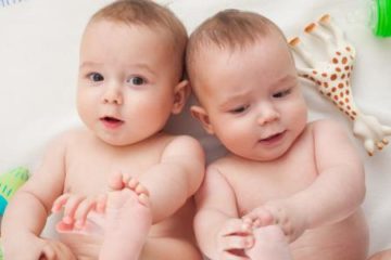Twin baby boys holding feet