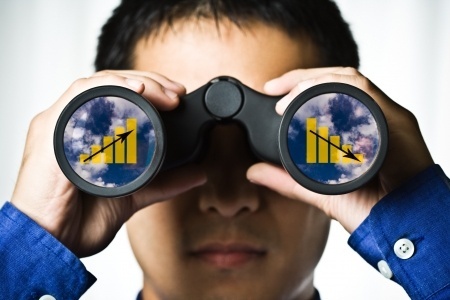 Man peering through binoculars with graphs in lenses