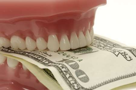 mold of teeth biting several $100 bills