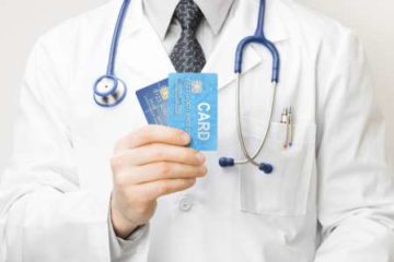 Physician in lab coat holding credit cards