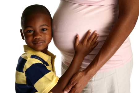 young boy holding pregnant mother's belly