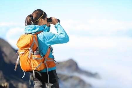 Woman on mountaintop looking through binoculars