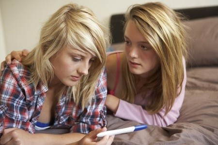 Teenage girls reading positive pregnancy test