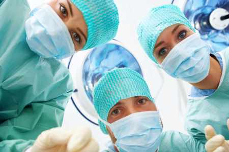 Group of medical professionals looking down at surgical patient