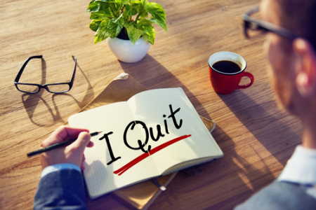 Man writing "I QUIT" in bold letters on notepad