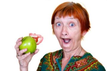 Elderly woman with dentures stuck on an apple