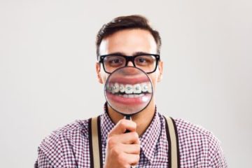 man with braces looking through magnifying glass